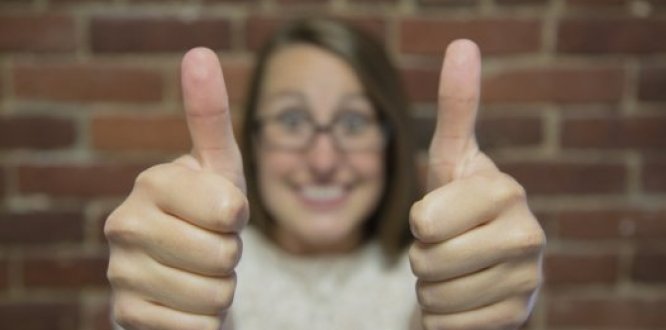 Mujer sonriendo con ambas manos levantadas con el pulgar arriba
